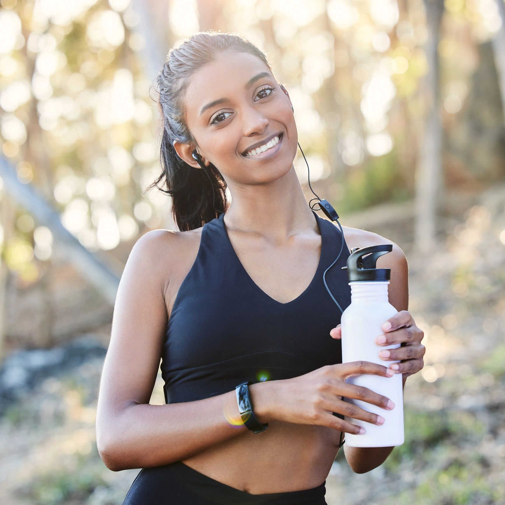 Woman drinking water outdoors after a workout