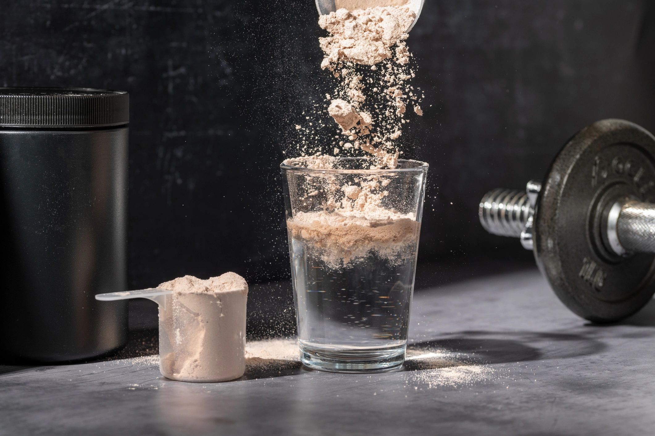 Chocolate protein powder being poured into a glass, representing smooth dissolving protein